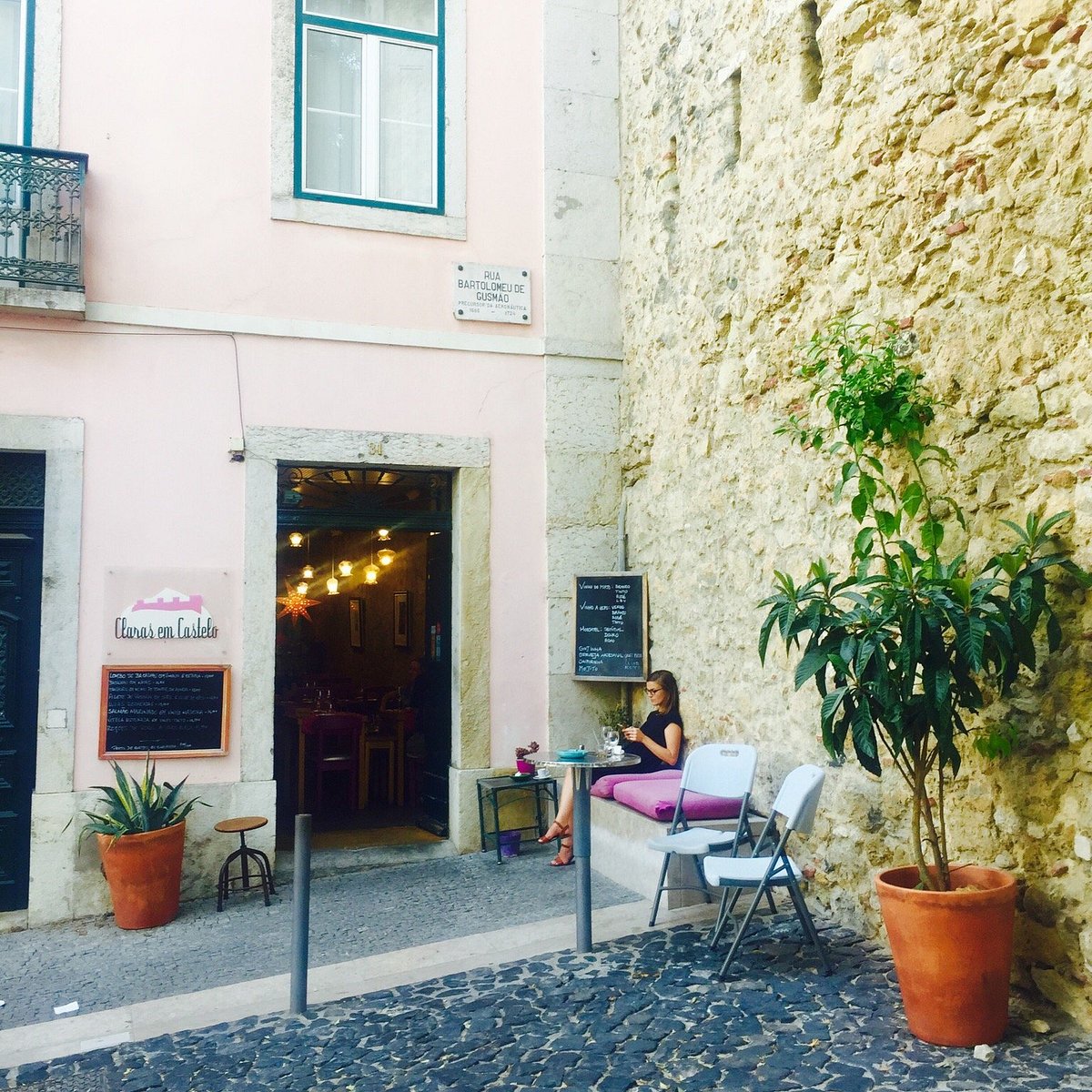 Entrada do Claras em Castelo, com fachada rosa, plantas e calçada portuguesa